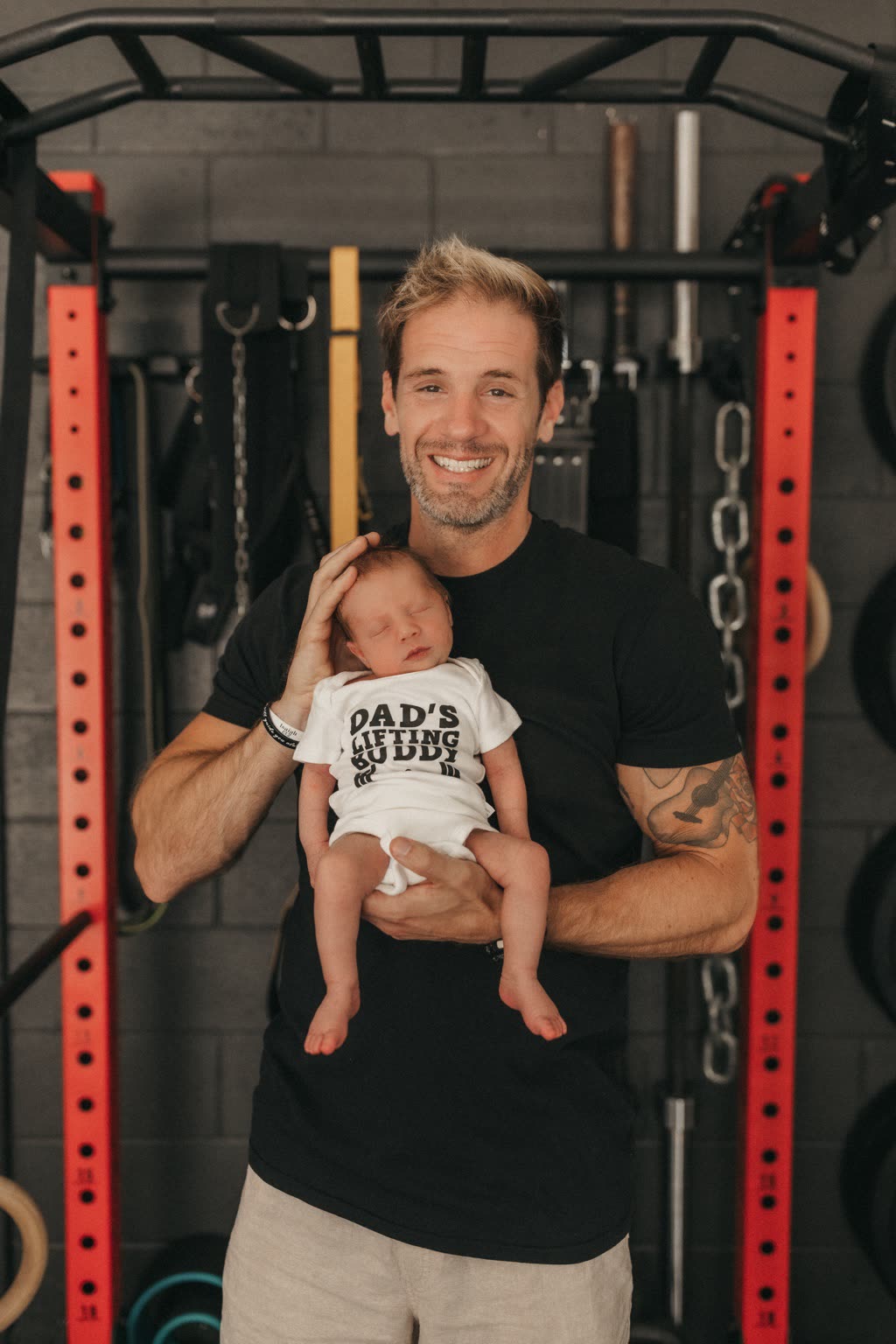 Nick holding his newborn son Malachi in his private gym