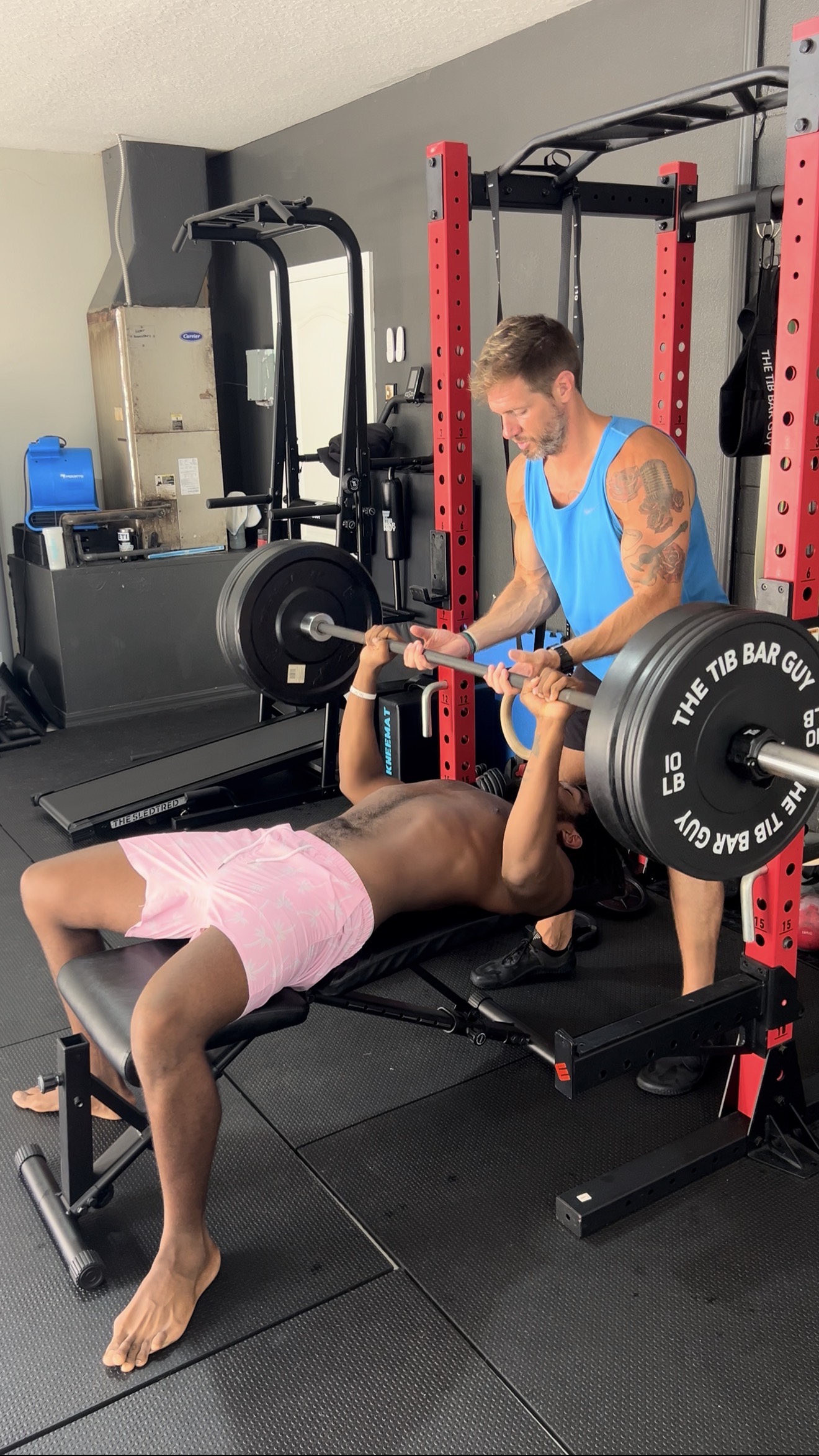 Nick coaching and spotting a college athlete during a bench press