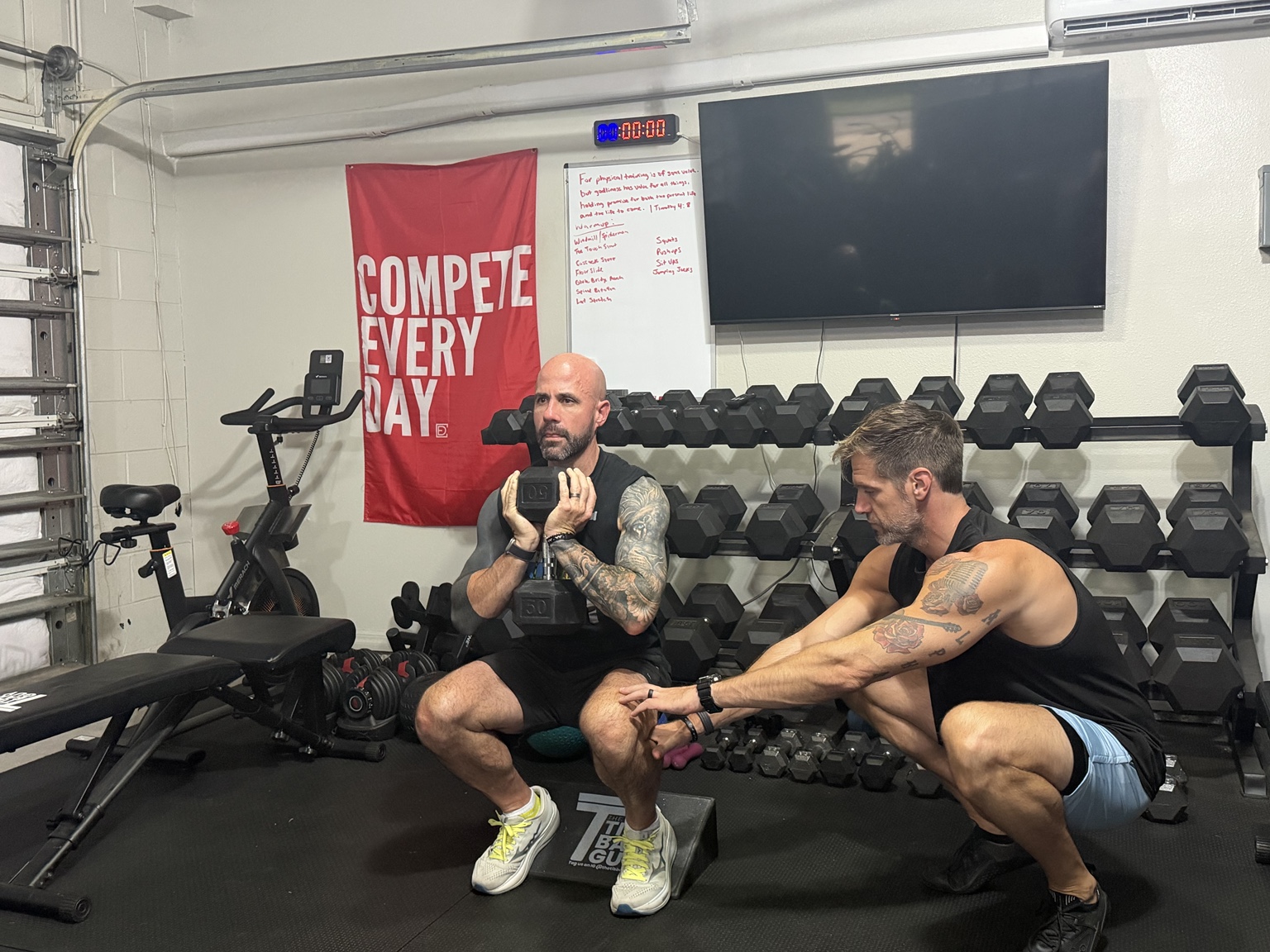 Nick closely coaching a client through a controlled dumbbell squat