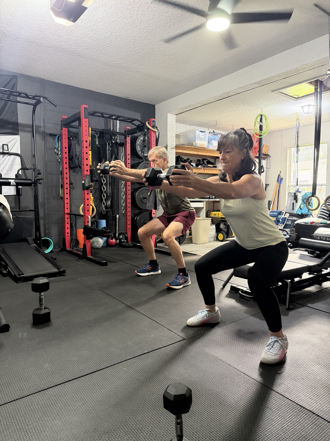An adult couple strength training side by side in Nick’s private gym