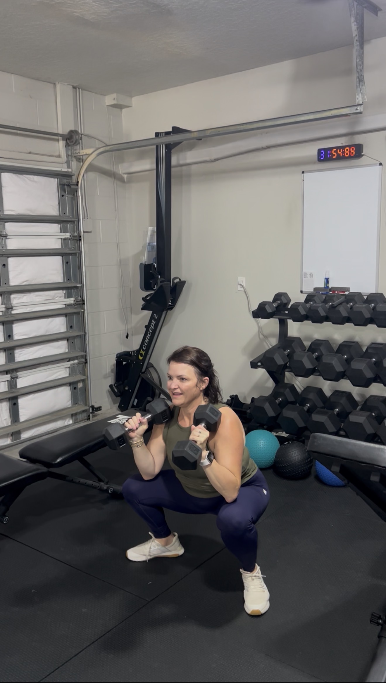 A woman performing a dumbbell squat in Nick’s private gym